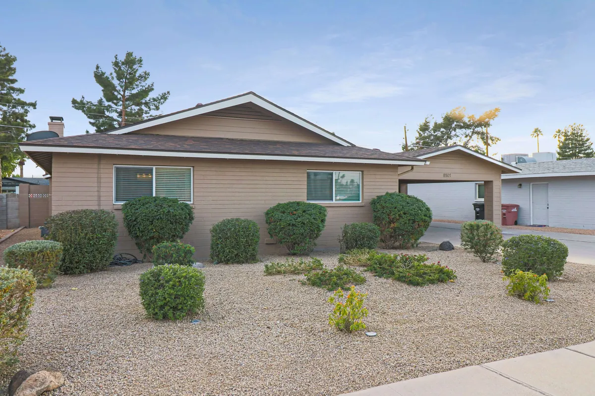A view of the home's inviting facade, framed by well-maintained shrubs and a spacious driveway. The front yard exudes a warm, welcoming atmosphere, perfect for gatherings or simply enjoying the Arizona sun from the front porch.