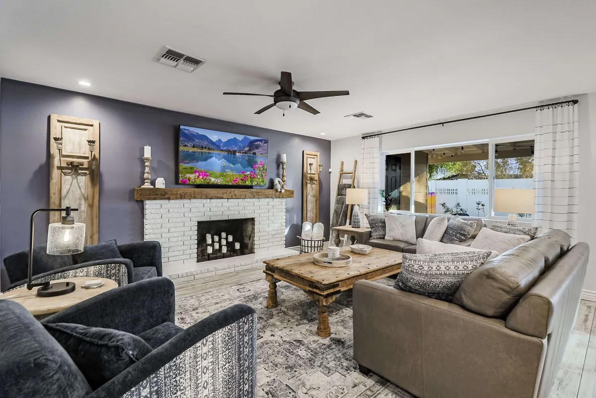 This image features a spacious living area with a comfortable sofa seating arrangement, a wooden coffee table, a TV set above a sleek fireplace, and large windows letting in natural light. The decor is warm and inviting, ideal for relaxing or enjoying a movie night together.