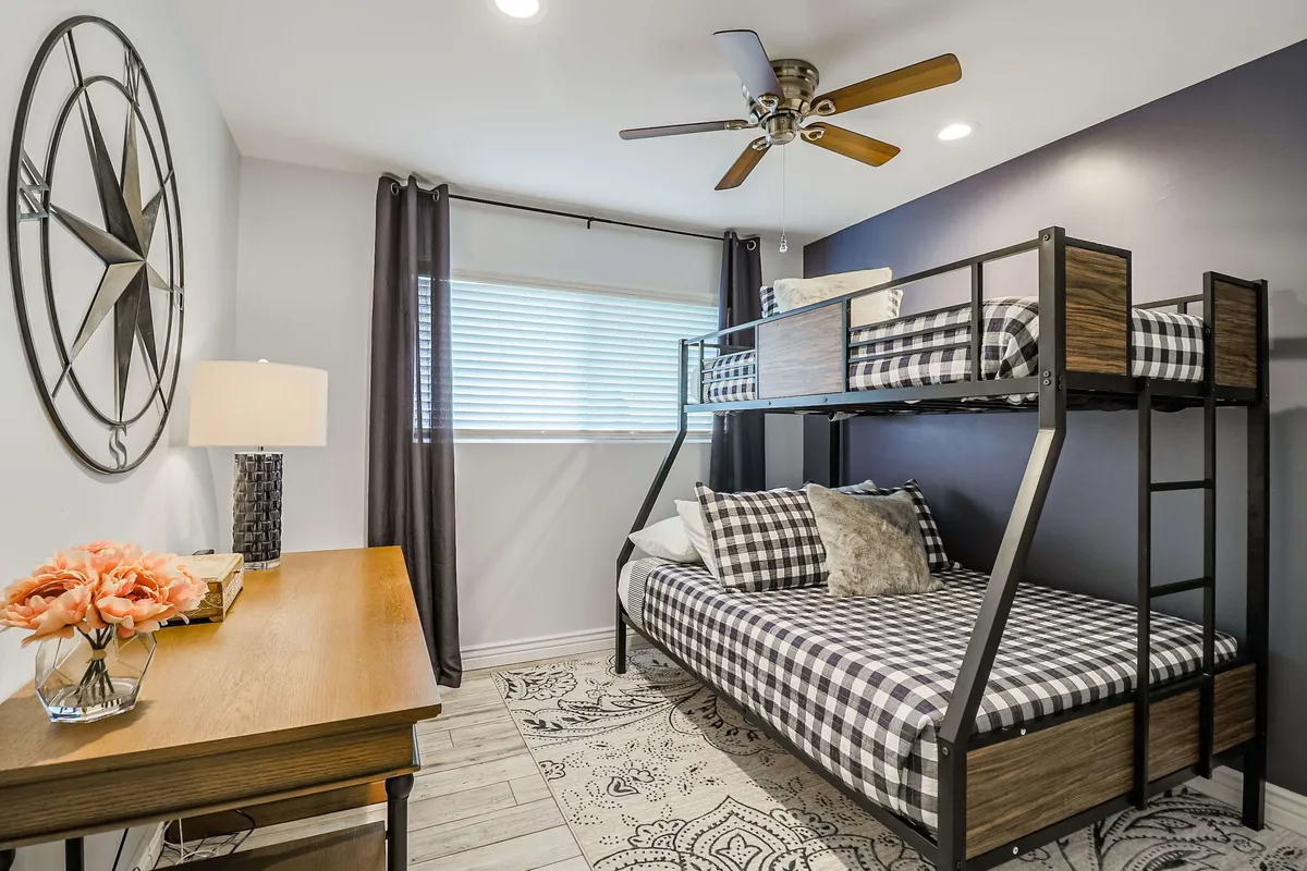 A versatile bedroom setup with a bunk bed and a functional desk area, complete with a decorative wall clock and a cheerful floral arrangement. The space is playful yet practical, ideal for both sleeping and productivity, echoing the dual-purpose design described in the section.