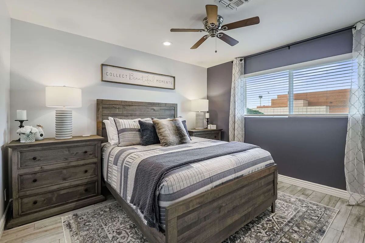 A serene bedroom space with a bed adorned with decorative pillows, a nightstand with lamp, and peaceful wall art. The atmosphere is cozy and restful, suggesting a quiet spot to unwind and recharge.