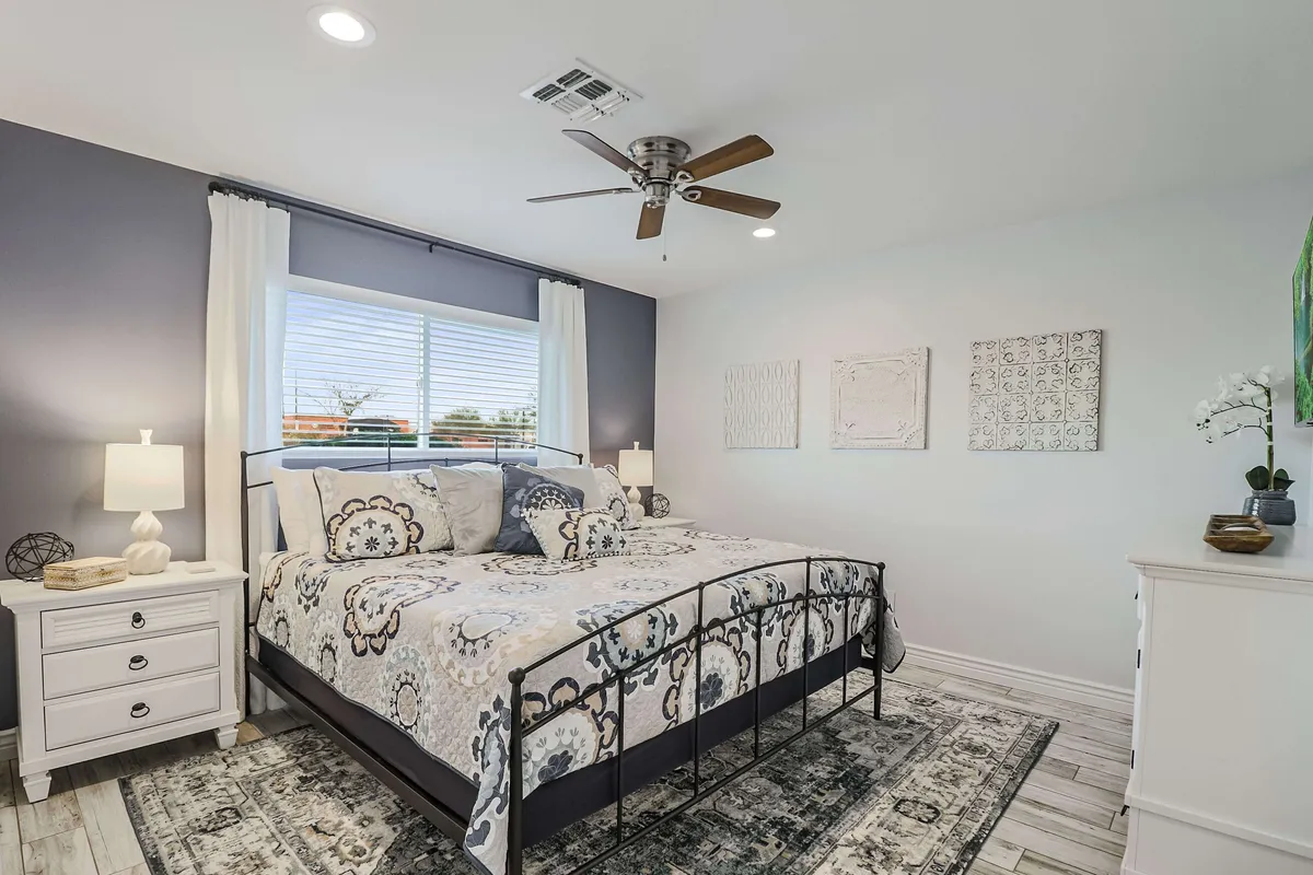 A serene bedroom featuring a well-made bed with decorative bedding, flanked by nightstands and lamps. Natural light streams in through a window, while tasteful wall art adds a touch of elegance. The inviting atmosphere suggests a restful haven for relaxation or winding down after a long day.