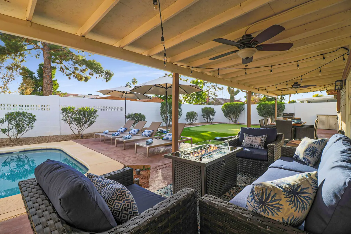 This image highlights a sparkling swimming pool surrounded by comfortable lounge chairs and an outdoor seating area, complete with a cozy fire pit. The setting is casual and inviting, perfect for relaxation or poolside gatherings. Sunset hues add to the tranquil and resort-like ambiance.