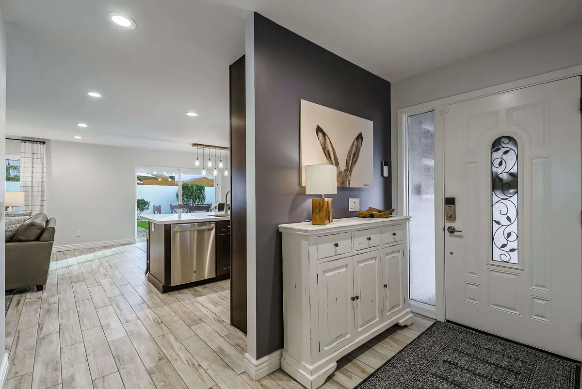 This image features a welcoming entryway with a wooden console table, decorative lamp, and playful rabbit ear artwork next to the front door. The space feels inviting and is clearly designed for greeting guests or marking the transition from the outside world into the home.